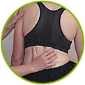 A person wearing a black sports bra is being examined or assisted by another person, who has one hand on their back and another on their side.