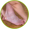 A person uses both hands to hold and stretch their left foot, which is bare and resting on a brown surface.